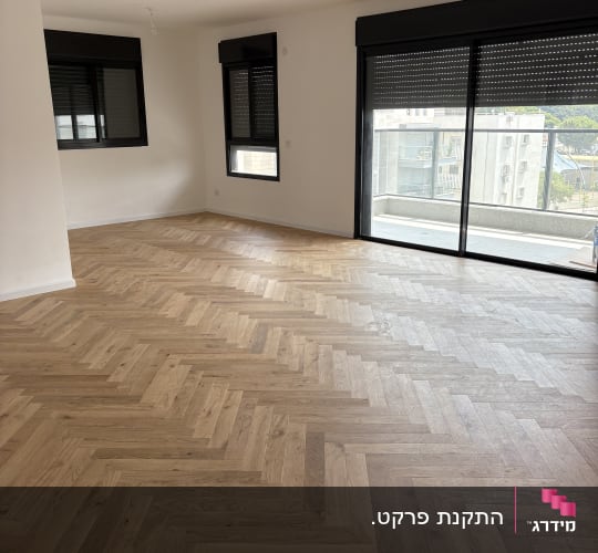 רצפת פרקט מעוצבת בחדר ריק עם חלונות גדולים